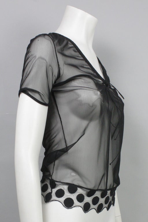 Short sleeved sheer blouse with drawstring at neckline and polka dotted hem.