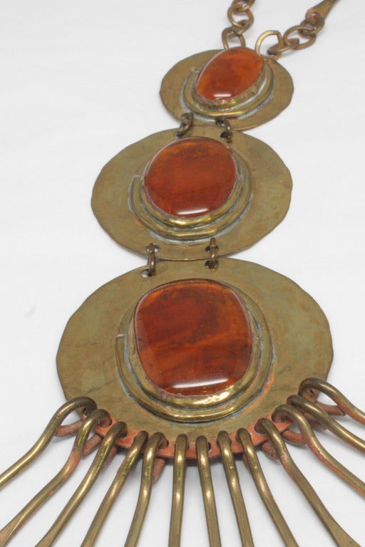 Orange glass cabochon and brass necklace by modernist jewelry designer Rafael of Canada, who designed for Liberace and Prince among others. This necklace features a pendant of three large pieces of murano glass and hammered brass discs with dangling