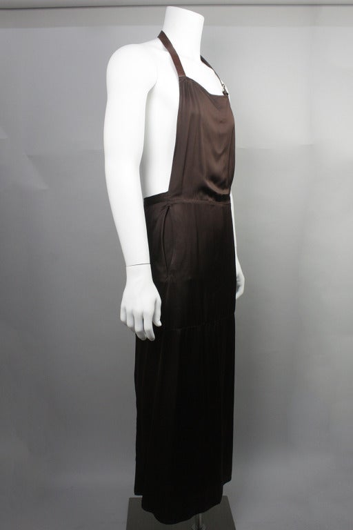 Jean Paul Gaultier è noto per il suo tocco di moda maschile e questo abito con grembiule ne è un perfetto esempio.  Questo abito marrone a grembiule in rayon è dotato di  cinghie in pelle al collo e in vita  Può essere indossato sopra i pantaloni o
