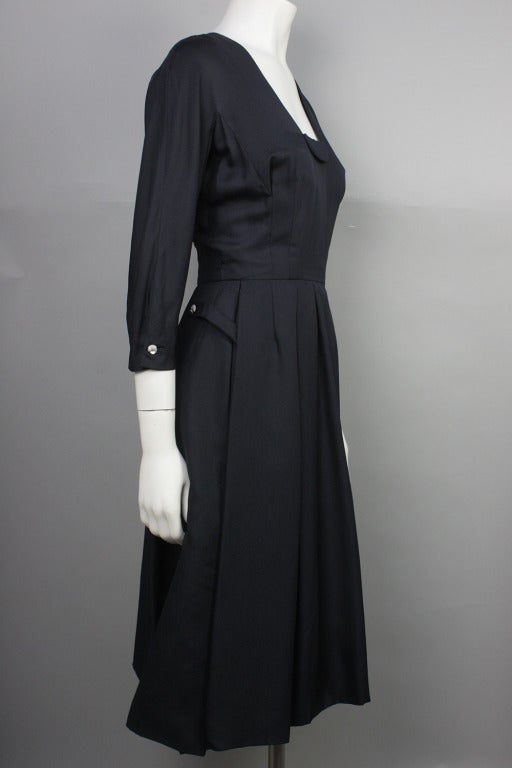 On sale! Originally $895

Beautiful navy blue silk taffeta dress with rhinestone swirl buttons at sleeves and hips.
