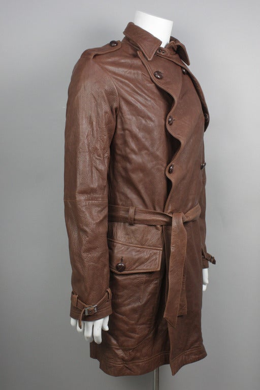 Luxe brown buttery Italian leather trench by Vivienne Westwood Man. Tie belt at waist. Unique and characteristically Westwood rippling detail at buttons.