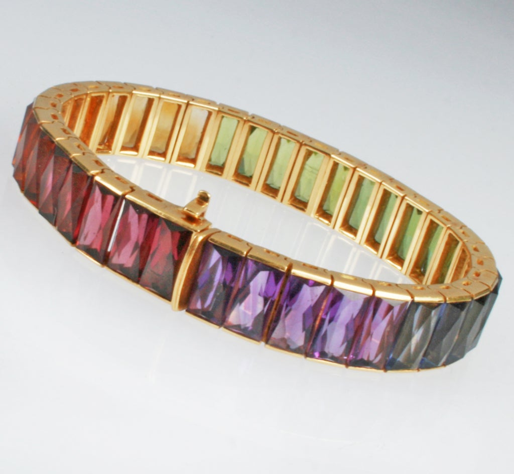 This is a gorgeous bracelet comprised of 36 individually mounted faceted stones. Amethyst, peridot, tsavorite, citrine, watermelon tourmaline and iolite are the stones that beautifully gradate in color. It has a safety clasp and is marked 750.