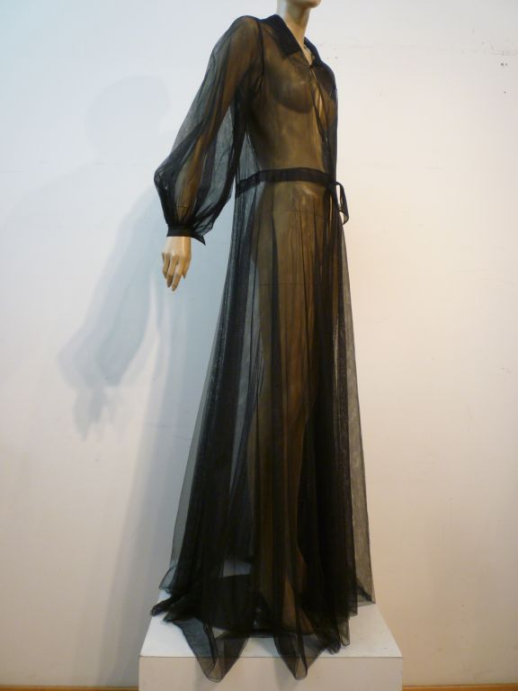 A black silk tulle négligée coat with tie at waist band and collar closure and balloon sleeve.  Size 6-8