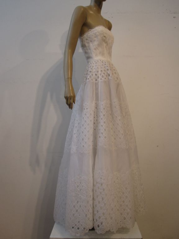 A gorgeous Oscar De la Renta gown sold at Saks Fifth Avenue.  Beautifully and simply constructed of white silk eyelet lace and organza in a graceful strapless silhouette, this would be a fantastic choice for a wedding or for the holidays! Marked