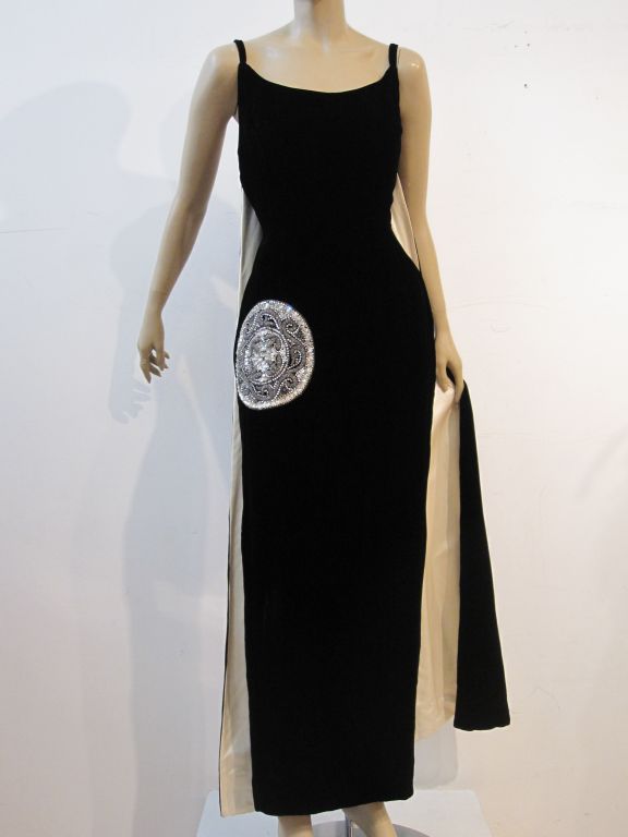 An incredible 1950s Mr. Blackwell Custom designed gown: Black velvet column with thin straps, back slit, and white silk satin lined back panels.  The gorgeous finishing touch is a minimalist beaded and sequined medallion on the right side of the