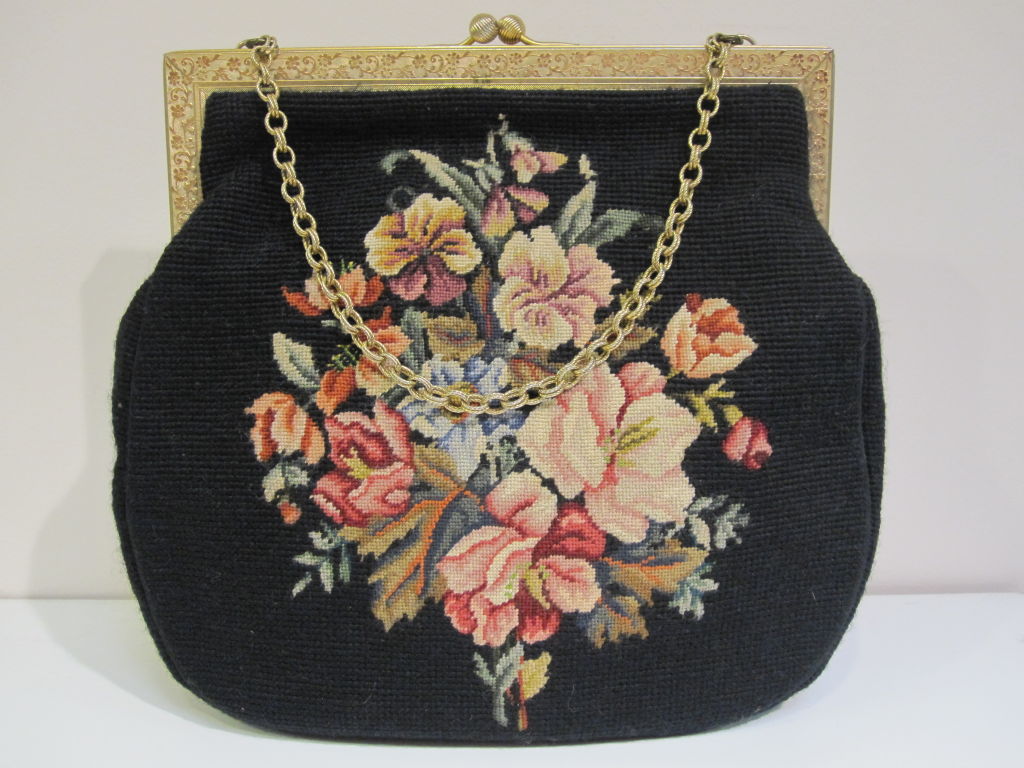 A wonderful 50s needlepoint daytime bag with gold frame black needlepoint background and multicolor floral motif petite pointe embellishment.  Gold faille lining and gimp edging.  Very large, measuring 13