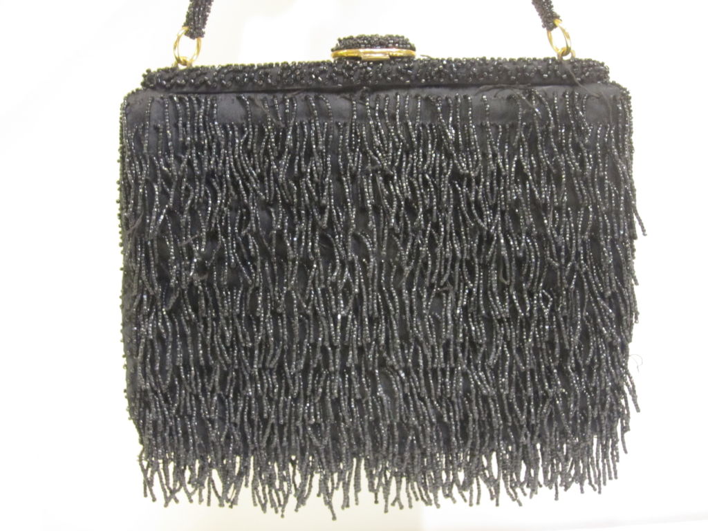 1950s black hand-beaded fringed evening bag.  Is actually jet black, with photo lightened to show fringe detail.  Black satin lining is in very good condition.  Fringe is in very good condition with a few missing toward top edge.  Measures 7.5