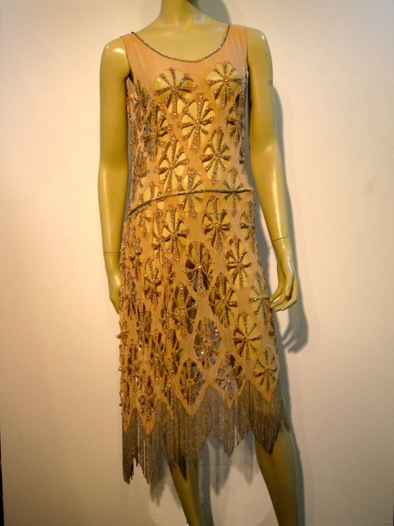 An extraordinary example of French fashion in the 20s in a  soft apricot color silk. Exquisitely and delicately cut and beaded geometric design and sawtooth hem with fringe.  In very good to excellent condition but very delicate.  Size 2-4