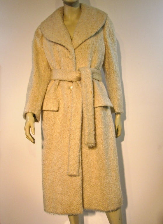 A wonderful early Norman Norell 50s shawl collar coat with tie belt in a beige and cream mohair tweed novelty fabric. Buttons in front and flap pockets.