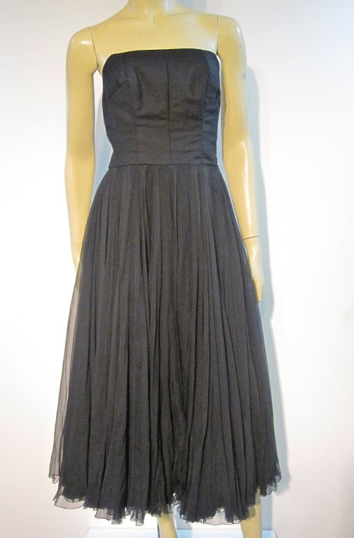 A gorgeous very early example of James Galanos' fine work. Label style indicates it was made between '51 and '55.  Very simple but extremely structured wool strapless bodice and voluminous silk chiffon skirt.  Skirt hem is completely hand surged. 