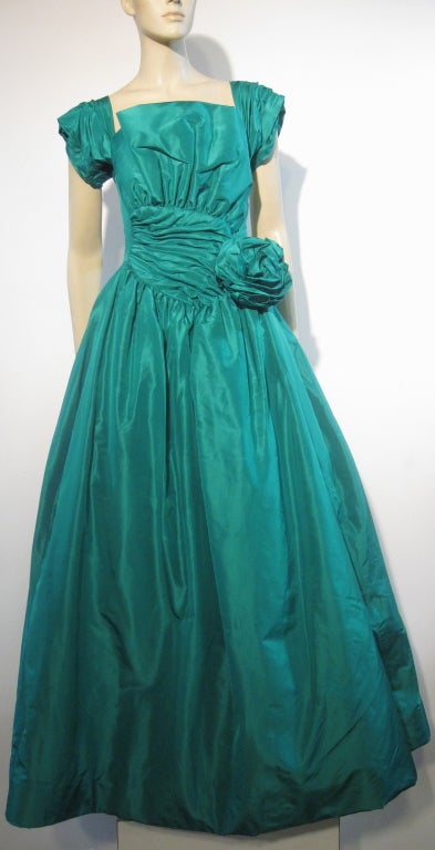 A fabulous Scaasi 80s silk taffeta ball gown in ruched emerald green (size 8) and an exquisite Elizabeth Arden 1950s floral silk and lame brocade evening coat with deep cuffed 3/4 length sleeves and extra long hem.  Shawl collar with no closures.