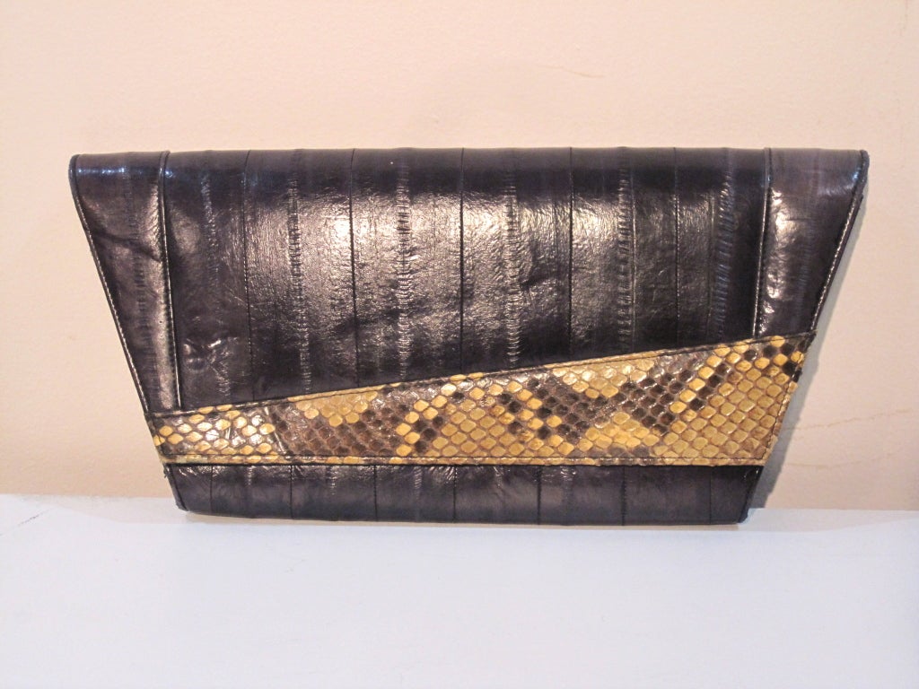 A striking 80s indigo blue eel skin and snake skin clutch in a dramatic geometric shape.  Suede lining with 2 zippered pockets.

Measures: 15