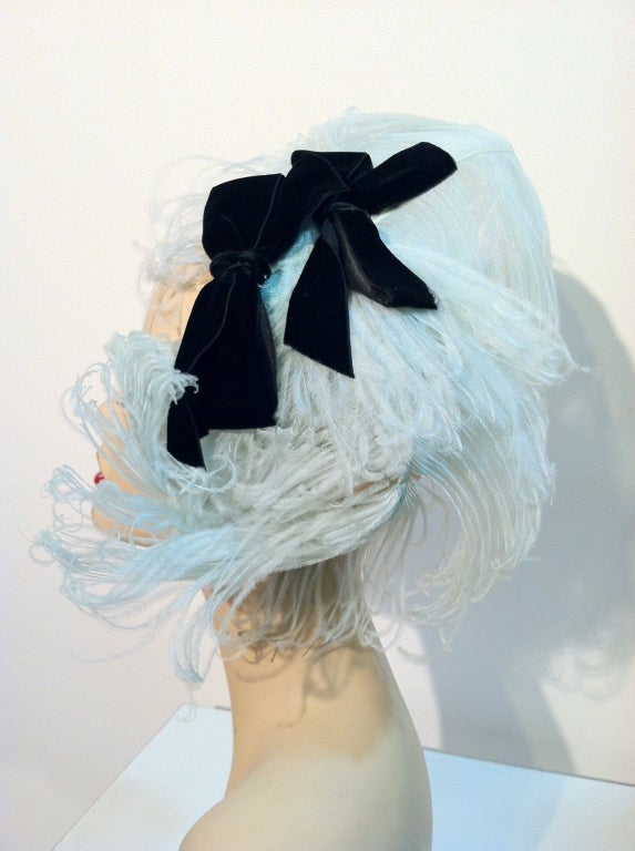 A fantastic 40s pale blue/green curled ostrich plume fascinator hat with black velvet bows, attached to a matching small round base.  Can be worn a variety of ways to suit your taste.