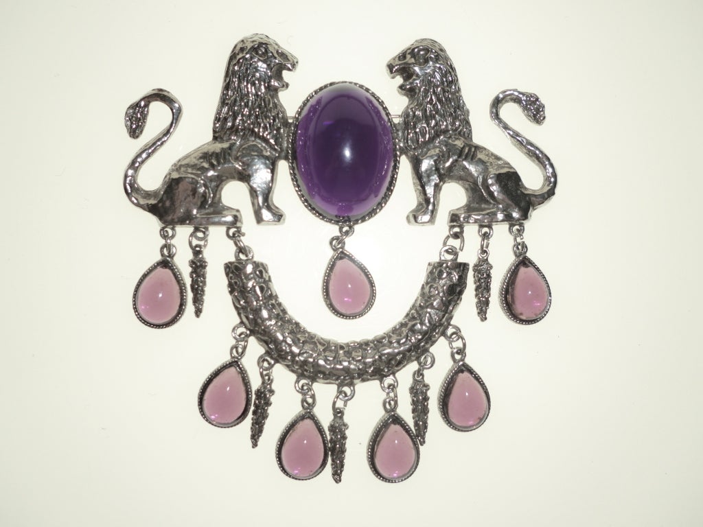 A 1970s very large dramatic Roman revival poured amethyst-color glass silver-tone metal brooch w/ symmetrical lions.  Measures 5