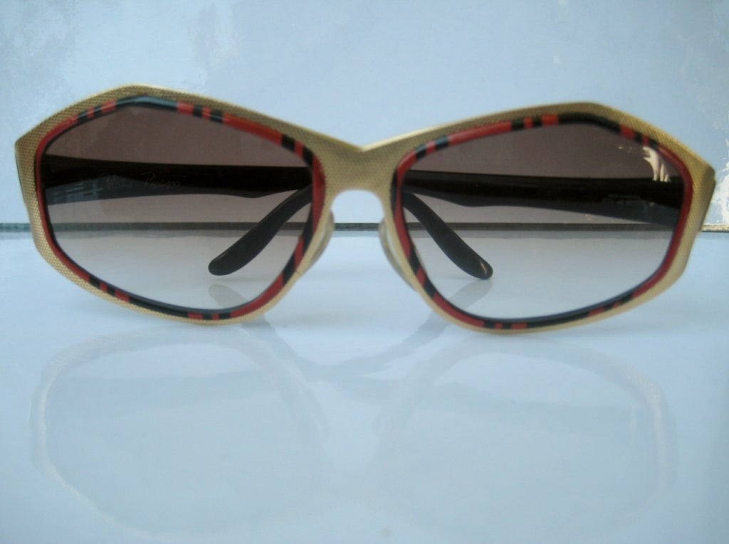 Angular in design...the lens is inset into a brushed gold frame.  Temples are striped red and black resin.
