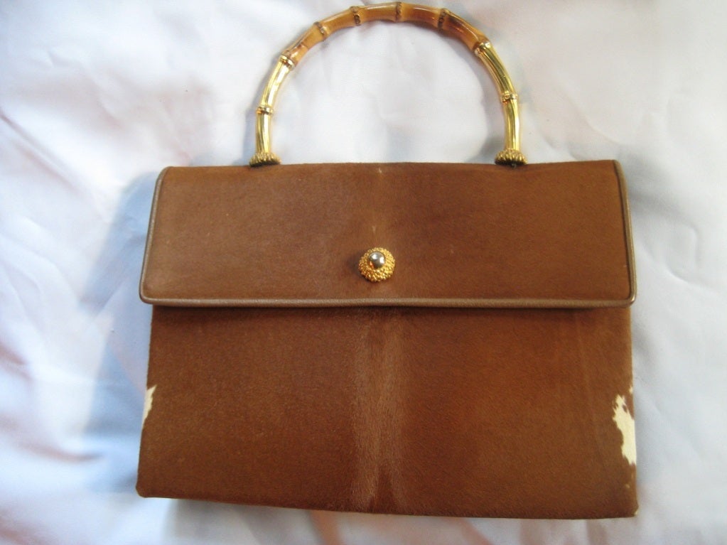 Truly AMAZING Calf Fur Handbag by Koret is lined in a shiny black leather interior with an attached coin purse.  Calf fur is supple to the touch and the most intriguing element is the elegant gold gilt bamboo handle.  Bag measures 12