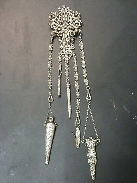 A beautiful Victorian chatelaine in elaborate sterling silver with a clip to go over a belt, this piece has 5 useful items hanging like charms to form a long piece measuring 14