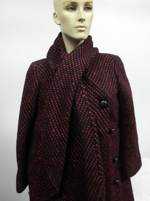 A wonderful red and black wool tweed coat with angled patch pocket, buttonholes inner tie at waist  and attached scarf.  Fully lined, this is cut on the bias in the front and buttons to one side asymmetrically.  The top button is slightly different