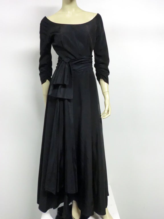 A fabulous unlabeled 40s evening gown in black rayon faille with ballet scoop neckline, back covered button closure, full sweep skirt, piped detail at waist and lovely pale blue satin lined ruffles from waist to hem in the back. Gorgeous!   Size 4-6.