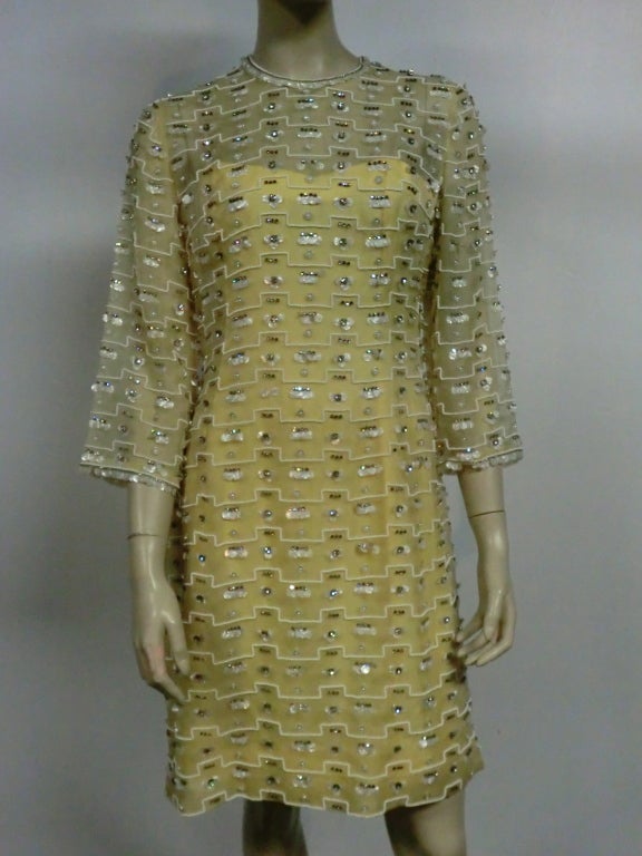A fabulous 60s Vegas style shift dress in pale yellow:  silk organza beaded, rhinestones and pearlized discs in a geometric pattern with 3/4 sleeves and matching under-dress.