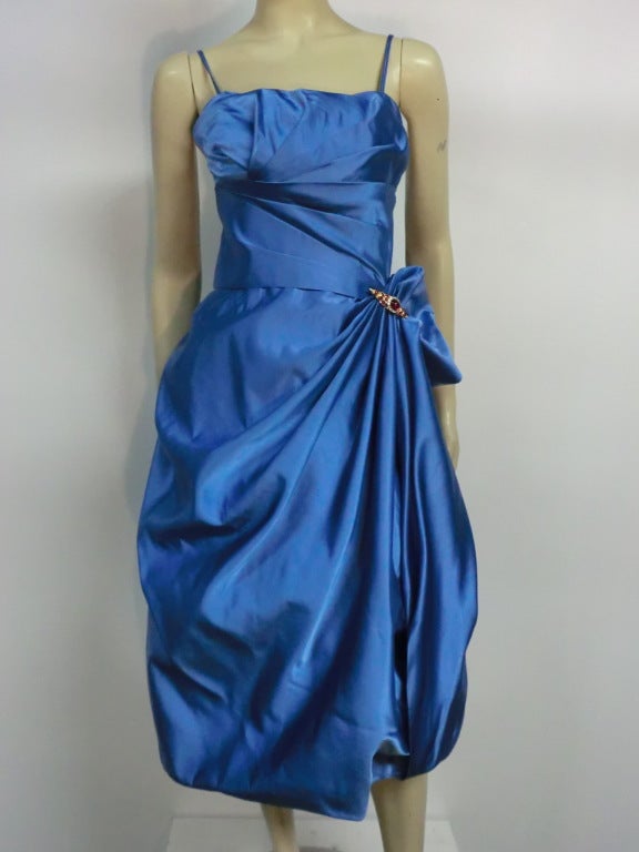 A wonderful 50s silk satin Ceil Chapman cocktail dress in azure blue with a gathered swagged hep bubble hem skirt, fitted waist and pleated bodice with spaghetti straps.