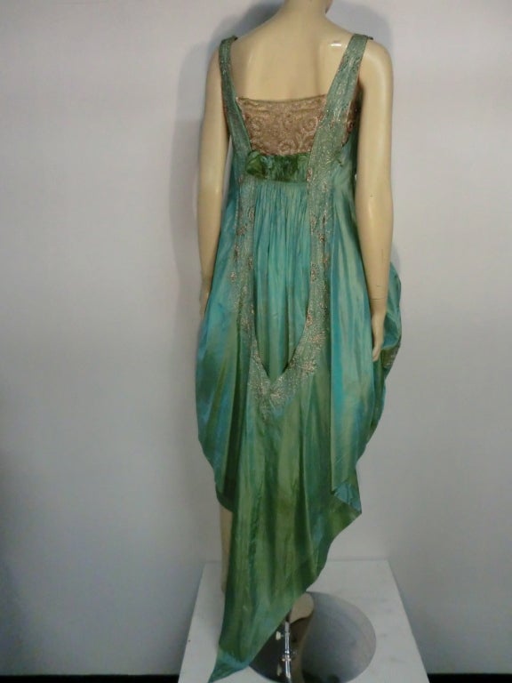 This gorgeous dress from very early 20th century is incredible!  It's not marked but is in the style and quality of Paul Poiret.  Green iridescent tissue silk with silver metallic couching and embroidered lace. Wrap front  with side closure. 