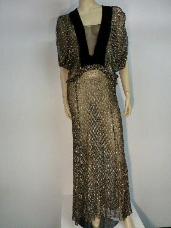 French quality metallic lace / mesh textile, in a heavier-than-usual weight, makes this 1930s gown flown beautifully!  The color is black with coin silver and it is trimmed with black silk velvet.  Arched dropped waist line with Grecian style draped