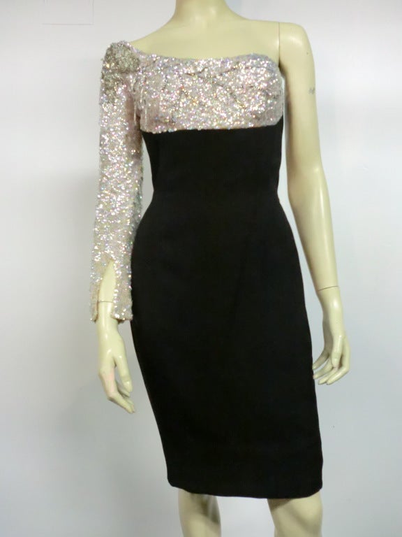 A wonderful custom made Mr. Blackwell cocktail dress: black silk crepe sheath with one-shoulder and sleeve, heavily embellished with sequins and beading. Zip cuff on the sleeve for a extra close fit.  Completely lined.