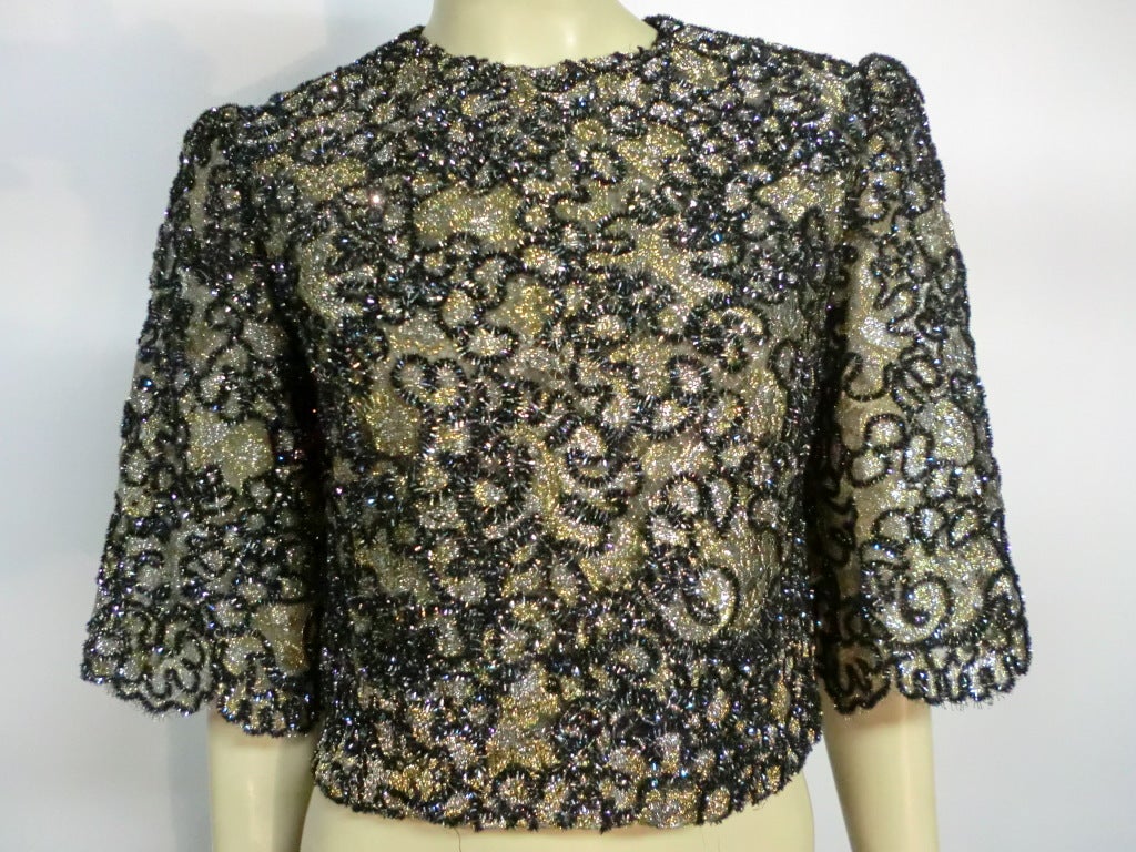 A pretty 1980s metallic chenille embroidered lace blouse that closes in the back with 3/4 sleeves and cropped waist.