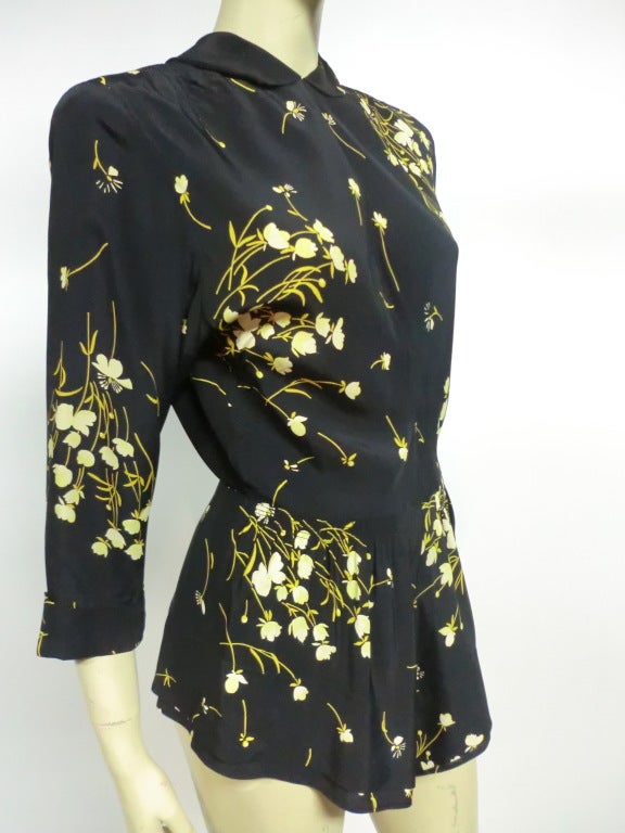 A great little 40s rayon crepe floral print blouse with collar, 3/4 sleeves and peplum .  Zips up the back.