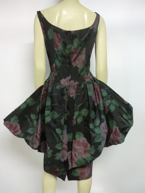 1950s rose print sheath dress in acetate with notched neckline and a graceful bubble peplum that is longer and fuller in the back.