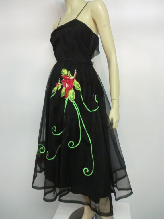 A great, 1950s Emma Domb black tulle party dress, fully lined, with spaghetti straps and full skirt.  Floral applique and green sequin stems adorn the skirt.