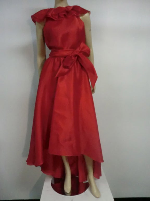 A fantastic mid to late 1970s Halston vibrant red silk organza dress with layers of luscious ruffles at the neckline, an angled hemline, belted waist and deep center slit to waist in back.  Great to wear with cigarette pants!