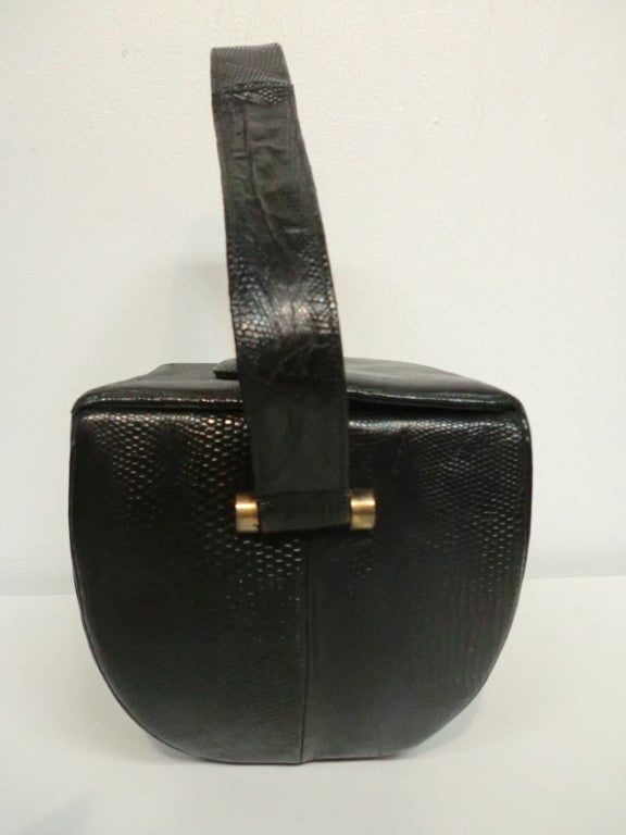 A sleek smart 1940s black lizard skin box bag with top flap closures. Black faille lining.  Gold tone metal twist lock. Great size for day or evening--carries all the essentials, but not the kitchen sink.  18 inch strap.