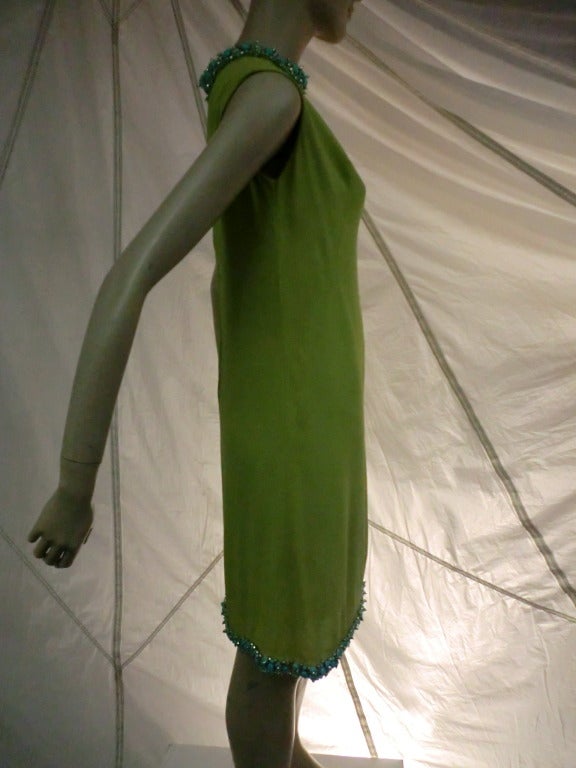 A beautiful 1960s mod shift dress of lime green silk crepe (lined) with back zipper and heavily embellished neck and hem trimmed in faux turquoise and pearl beads.  Sleeveless.