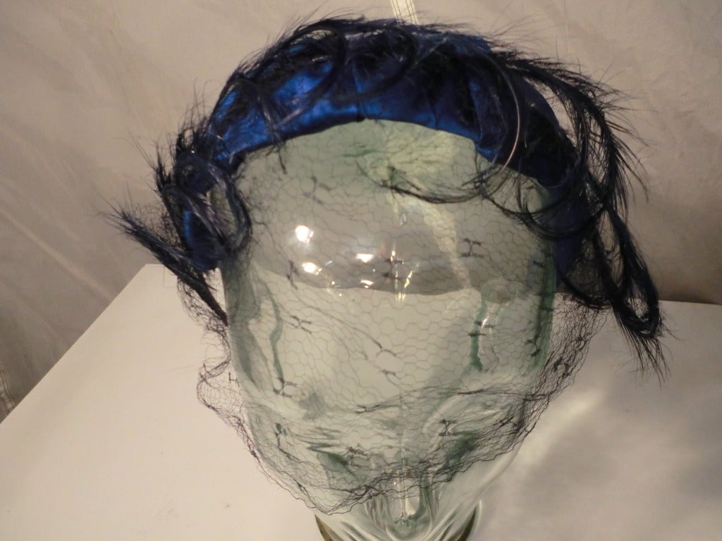 A gorgeous 1950s royal blue satin headband with curled navy blue feather embellishment and navy veil.
