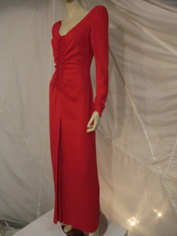 A vivid red 1980s Galanos red rayon crepe gown with ruched front bodice, front slit and pleating at center hem.  Zippered fitted and ruched cuffs on sleeves. Unlined.