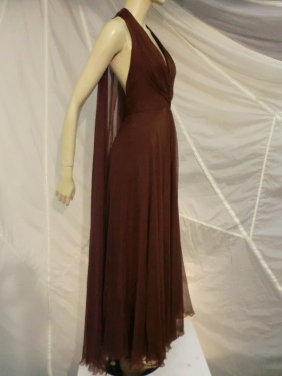 A gorgeous 1970s Mr. Blackwell silk chiffon halter gown with ruched front adorned with covered buttons and deep plunging back, covered by a flowing chiffon panel.