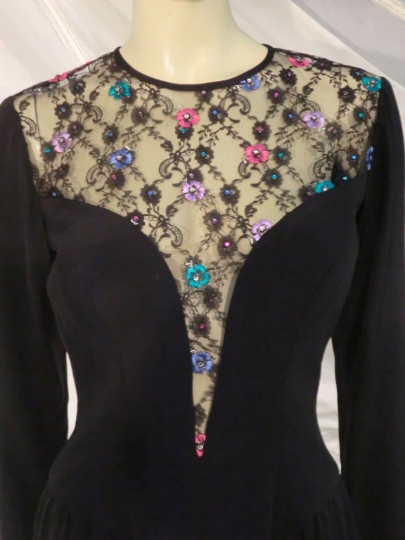 A 1980s Bob Mackie cocktail dress of black silk crepe with deep plunging sweetheart neckline and illusion lace top sprinkled with multicolor ribbon flowers.  Gathers at side of hips.  Back zip.