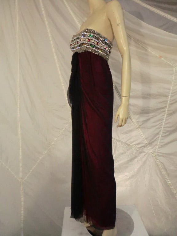 This incredible Galanos gown from 1965 is featured in the Galanos Retrospective book. The strapless bodice is heavily beaded and stoned with gold, red, green and clear stones and beads of various sizes and designs. The double layered skirt of the