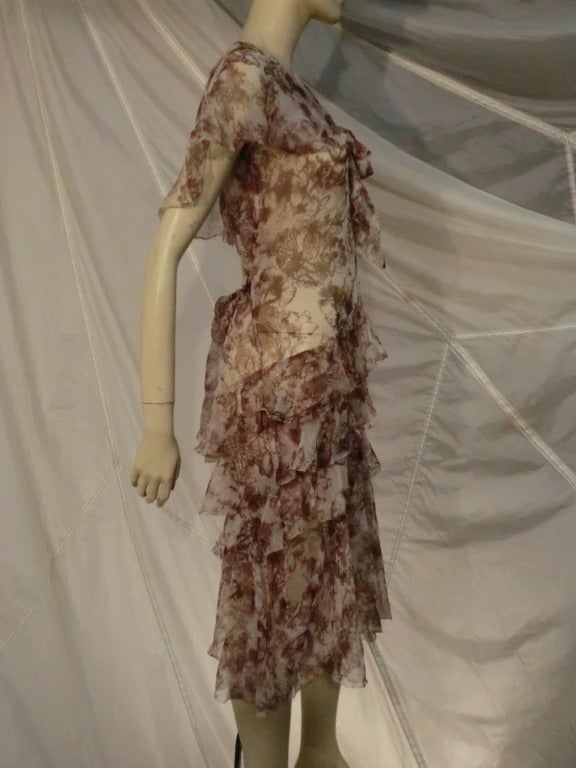 A wonderful 1920s tea dress in brown and cream floral print silk chiffon with tiered skirt and caplet sleeves.  Back waist tie.