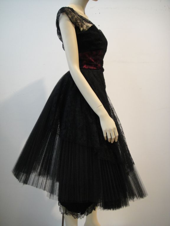 This is a truly spectacular Little Black Dress! This wonderfully delicate 1950's black sheath dress with fuchsia gathered inset sash bodice and lace overlay is marked 