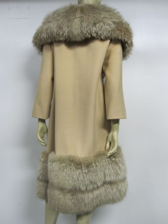 A fantastic 60s coat of beige wool with extravagant natural fox fur trim at the collar and hem. Details include slash pockets, and 