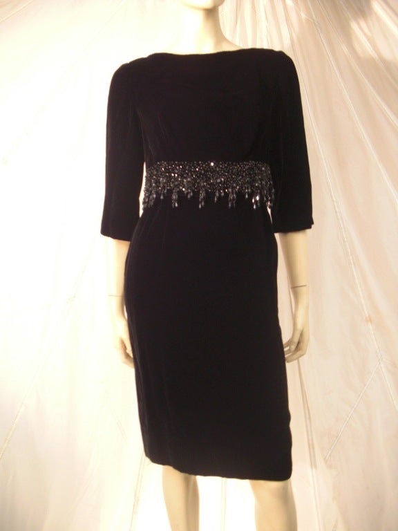 A beautiful two-piece 1960s black velvet cocktail dress with overlay: boat neck, bracelet length sleeves, back zipper and wide black beaded Empire waistline. Fully lined.