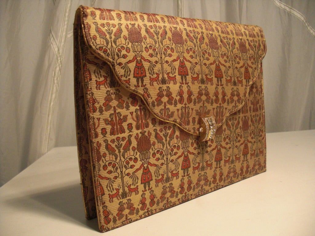 A beautiful 1930s figural silk brocade clutch purse with gold piping and rhinestone clasp.  Beige silk satin inside lining is in very good condition with on or two small spots.