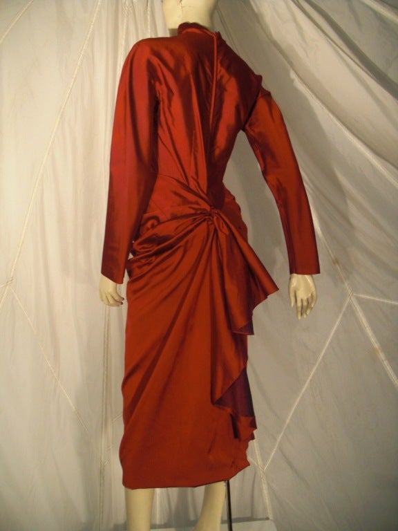 A fantastic 1950s scarlet silk faille cocktail dress with stunning back bustle detail, back zipper, high faux turtleneck and long zippered sleeves.  It is unhemmed (will be left to owner to decide how long to keep it).