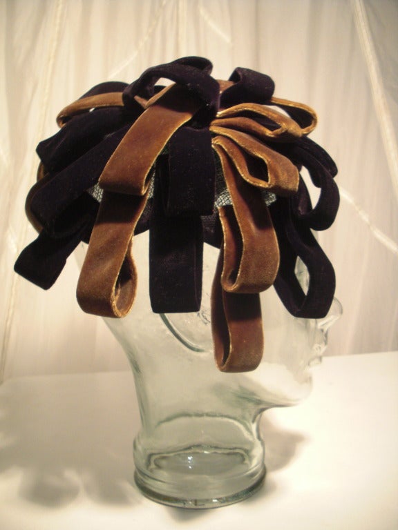 An interesting 1950s cocktail hat by Norma:  a velvet and tulle base is covered in rows of looped velvet in tobacco brown and black.  One size, this piece will need to be secured with combs or a hatpin.