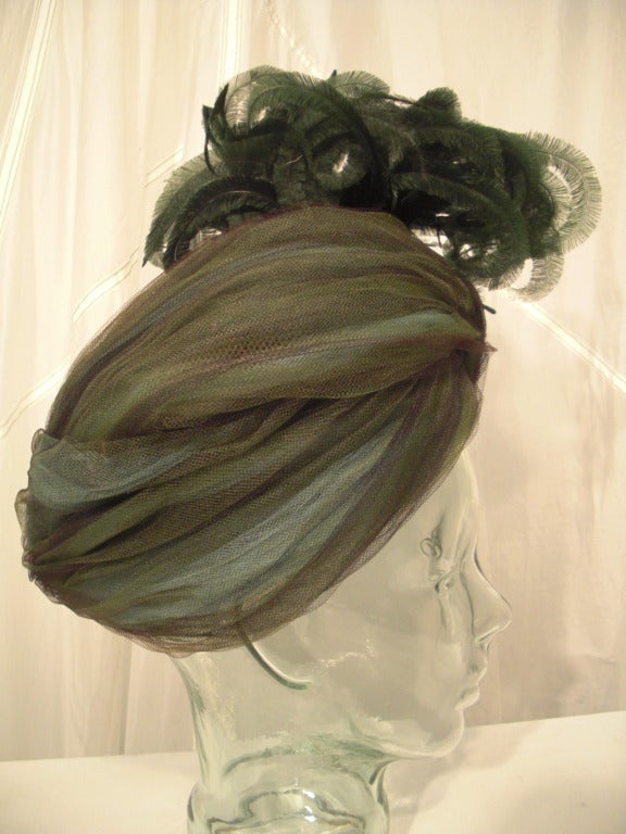 A fantastic 1950s regal tulle turban by Mr. Robert of silk tulle in a melange of teal, mint green, chocolate brown and grays.  At the peak is a mass of coordinating curled pin feathers!  Extraordinary!