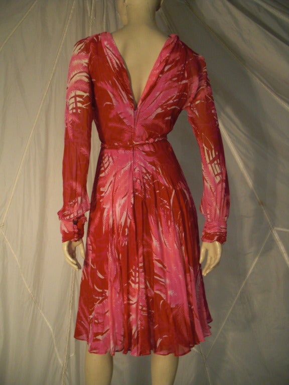 A beautiful early 1970s La Mendola fuchsia and pink palm tree print silk chiffon fit and flare dress with deep cut neckline and back and long sleeves. Fully lined. Matching 3 strand tie belt.