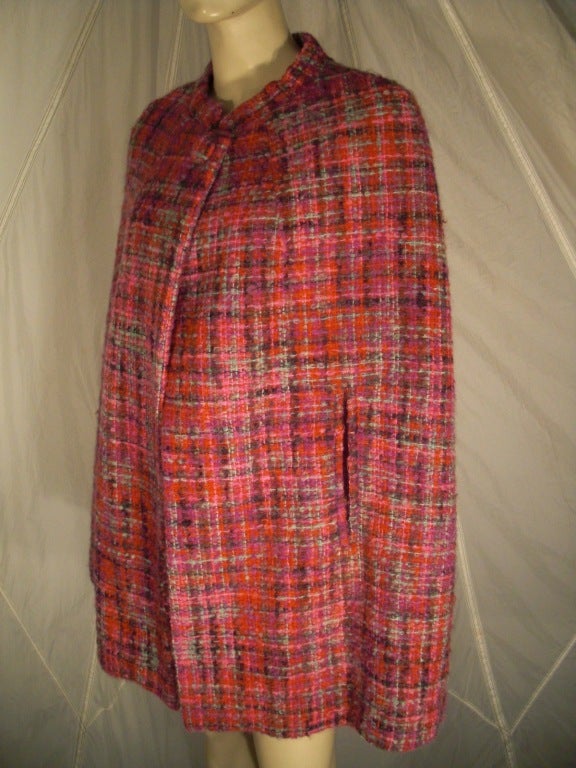 A smart 1960s pastel tweed cape to the thigh:  fully lined in silk w/ armholes.  Button closure and tab collar.